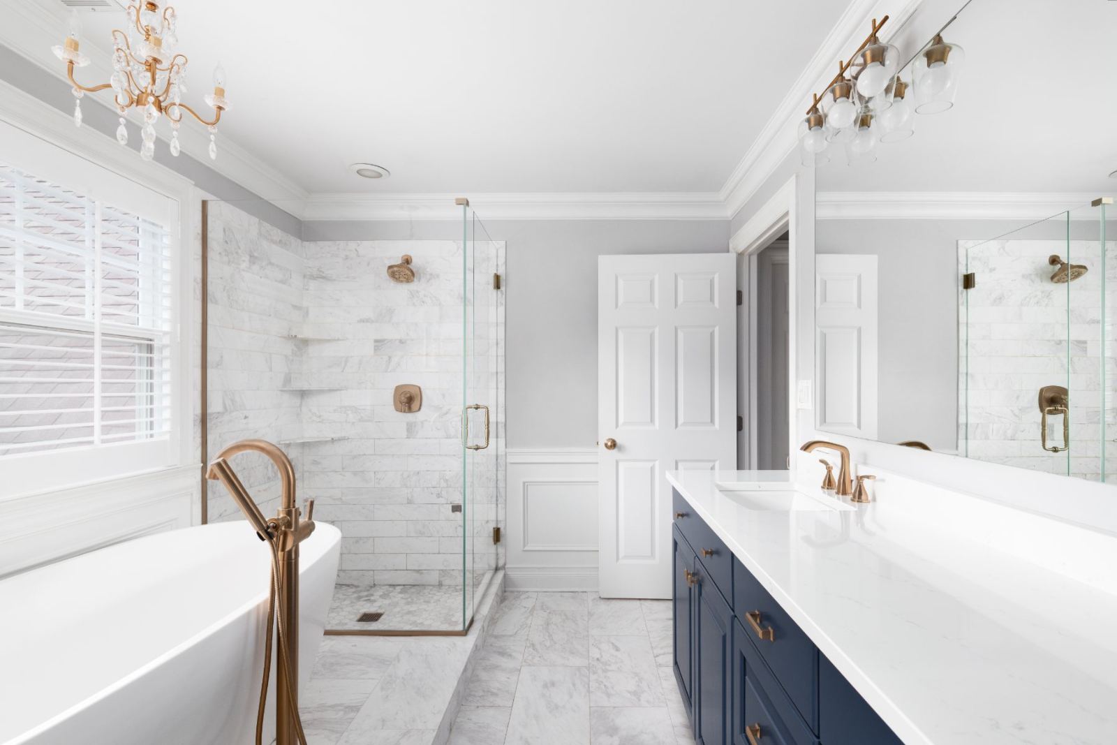 Luxury master bathroom with marble shower, dual vanity, freestanding tub, and brass fixtures