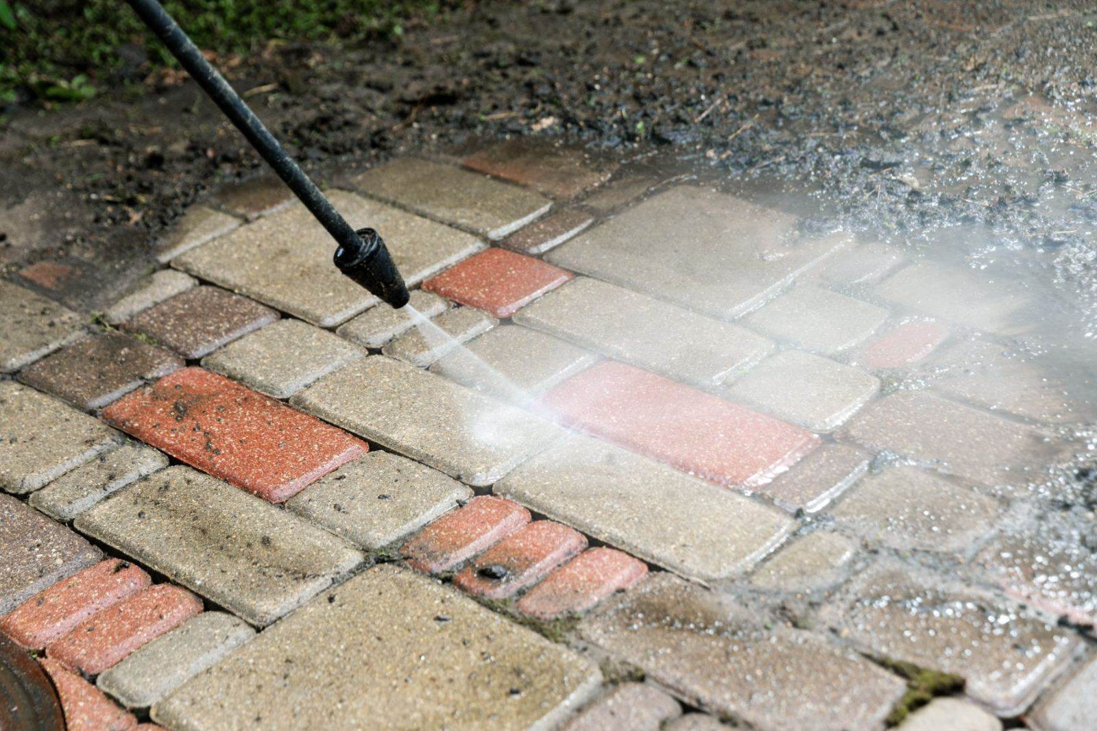 Pressure washing brick pavement with high-pressure water stream